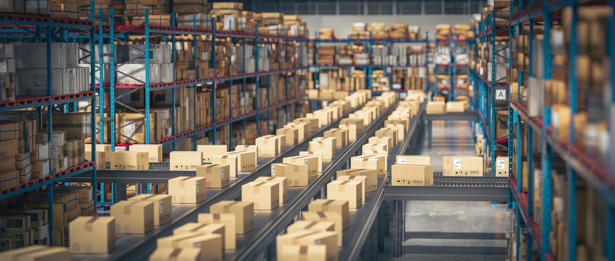 Cardboard boxes moving along conveyors between racking in a distribution warehouse