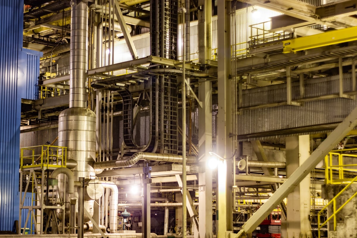 Industrial plant interior with process equipment and pipework, viewed from an elevated walkway