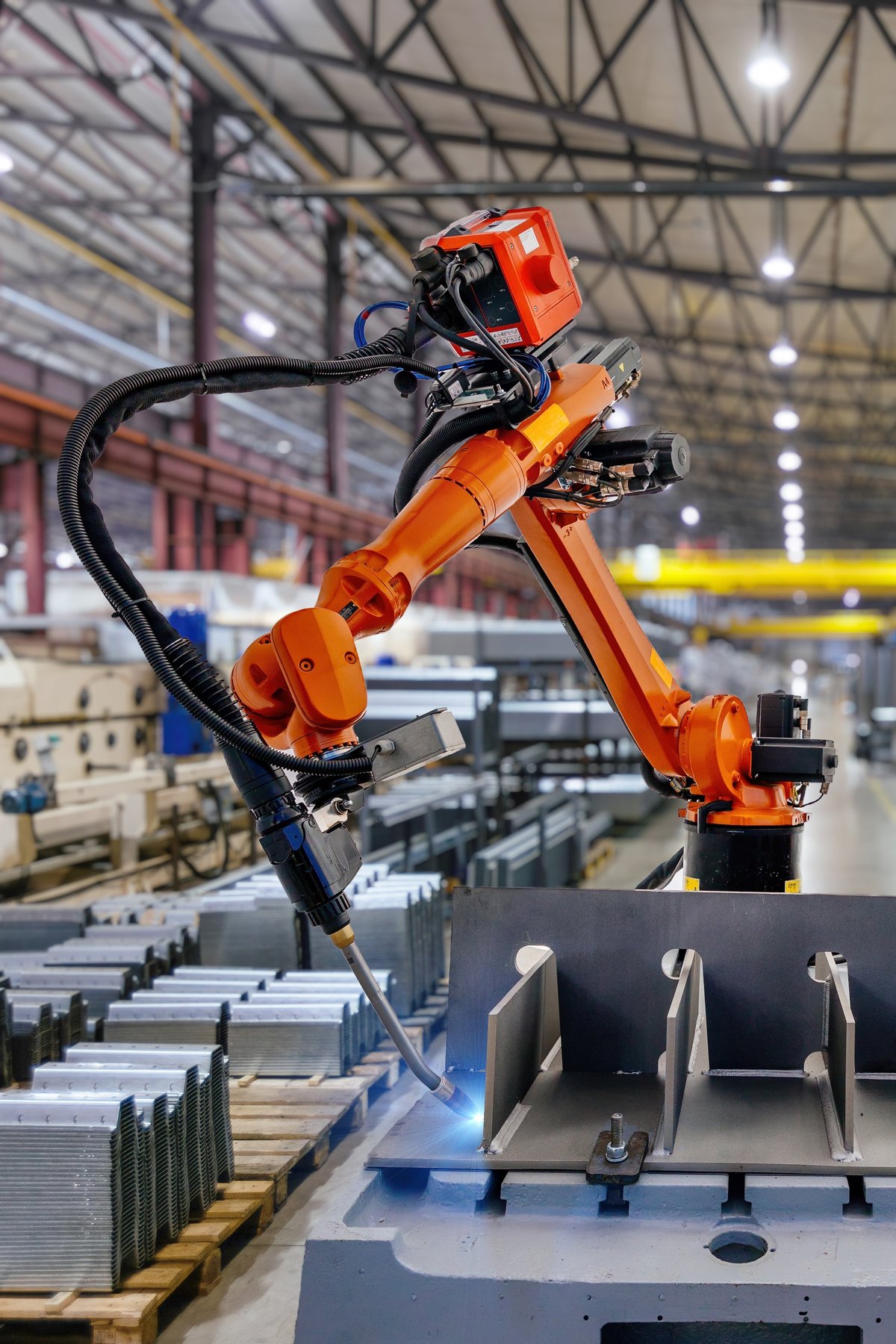 An industrial robot arm welding metal parts on a manufacturing production line