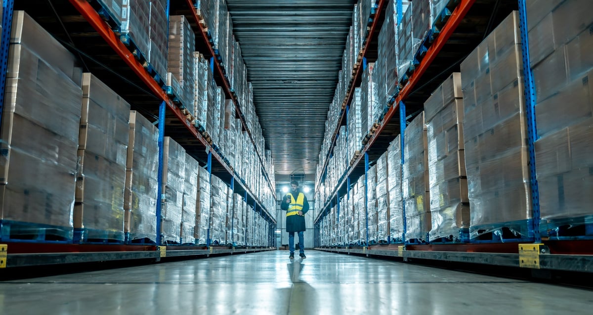 Worker scanning packages in an aisle of a cold storage warehouse