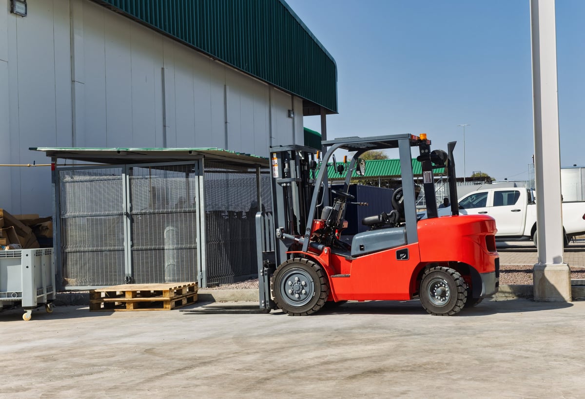 Forklift moving a pallet outside an industrial warehouse
