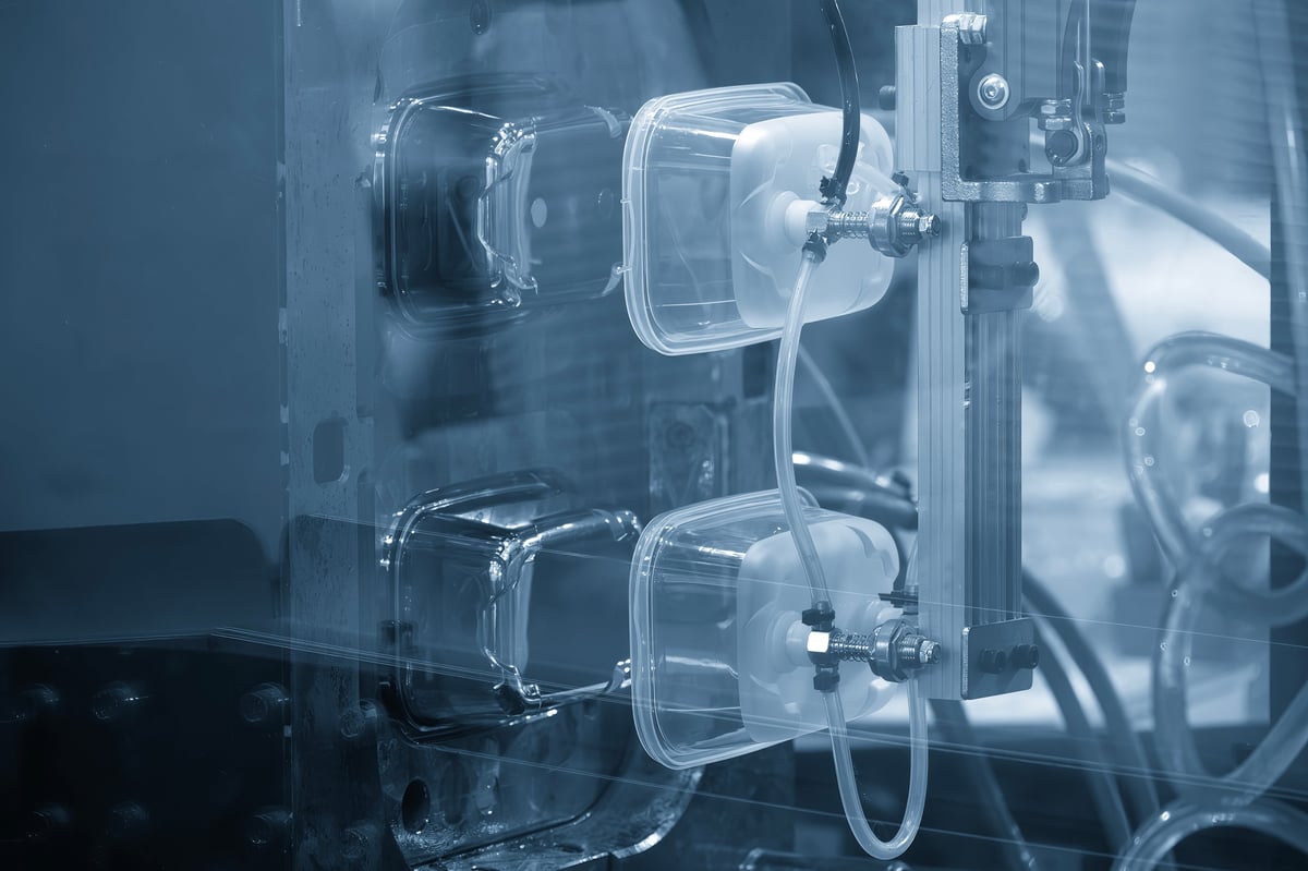 Close up of a material handling process moving food containers from an injection moulding machine on an automated production line