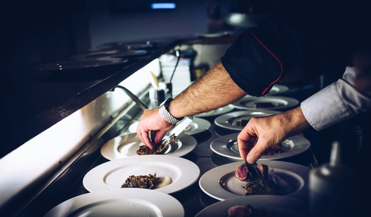Chefs arranging portions on plates in a professional kitchen