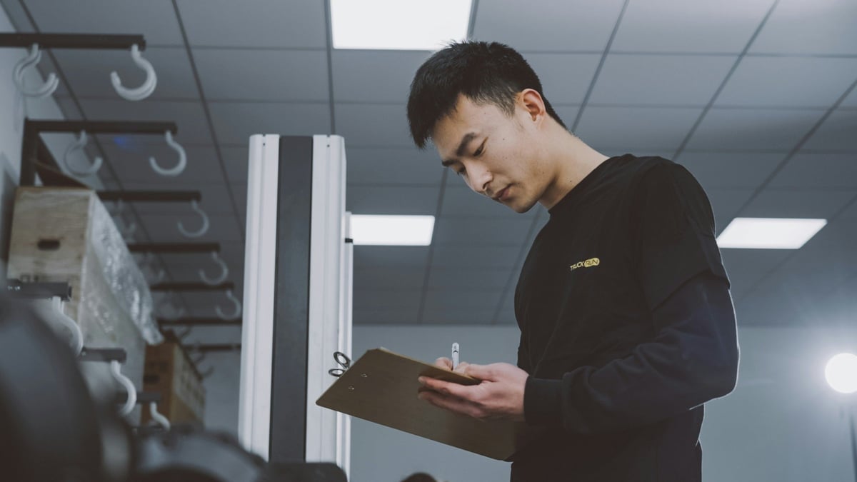 Worker recording information on a clipboard beside industrial equipment