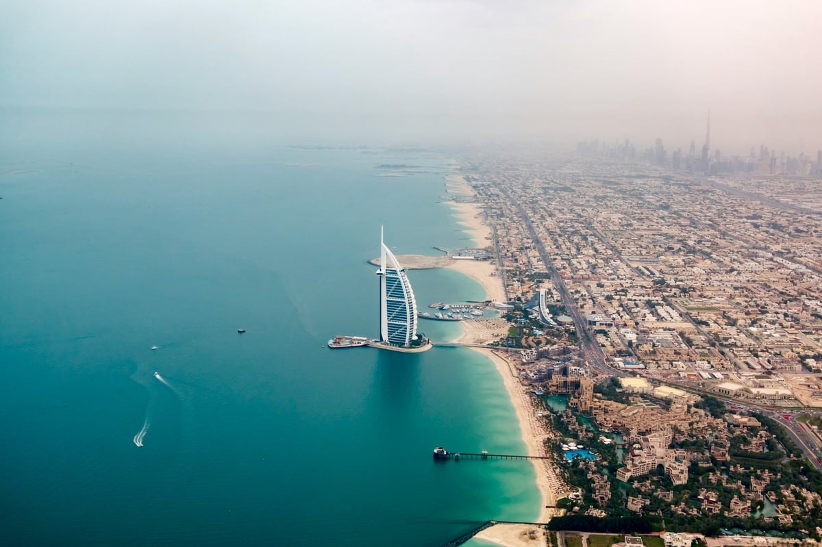 Aerial view of Dubai's coastline with the Burj Al Arab beside turquoise water