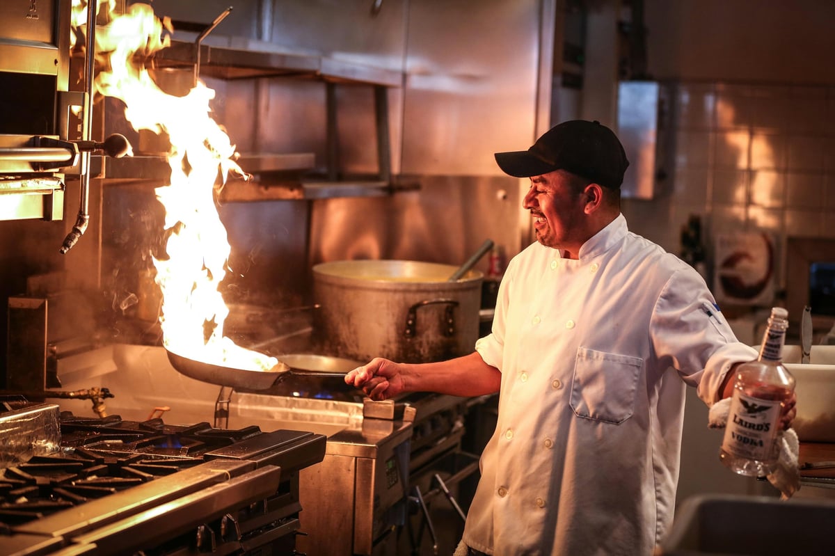 Chef cooking at a restaurant stove with flames rising from a pan