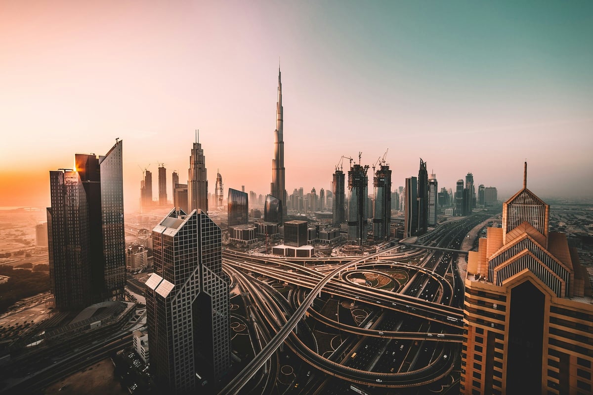 Dubai skyline and highway interchanges at sunrise, with the Burj Khalifa in the distance