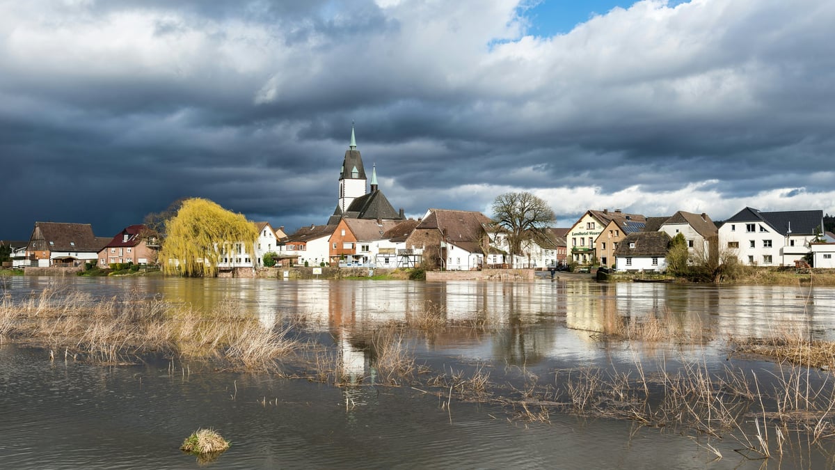 High water beside buildings in Höxter-Lüchtringen, Germany, beneath storm clouds
