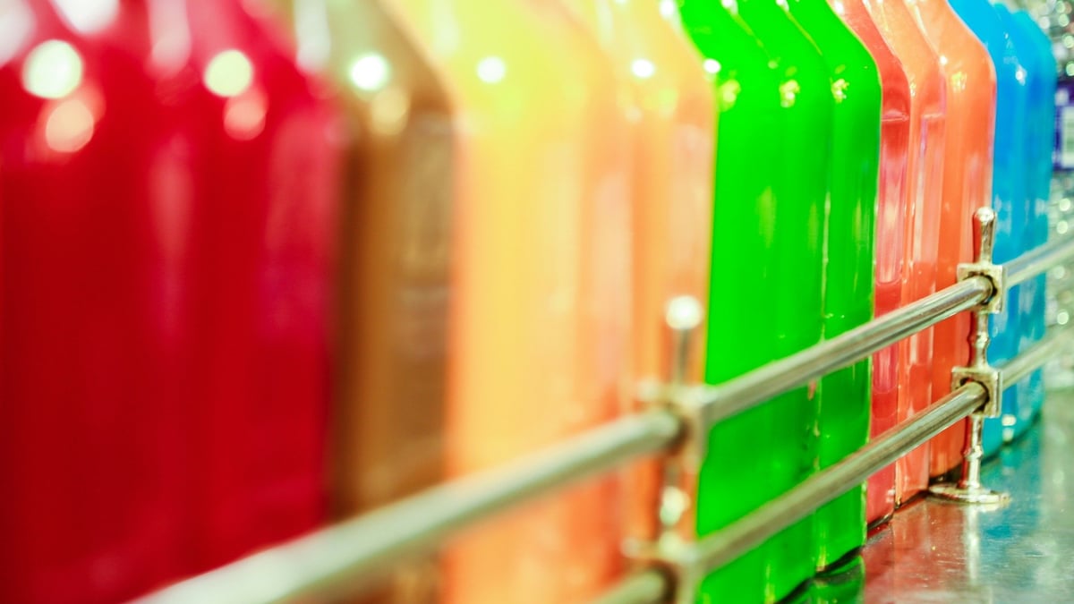 A row of colourful bottles behind a metal display rail