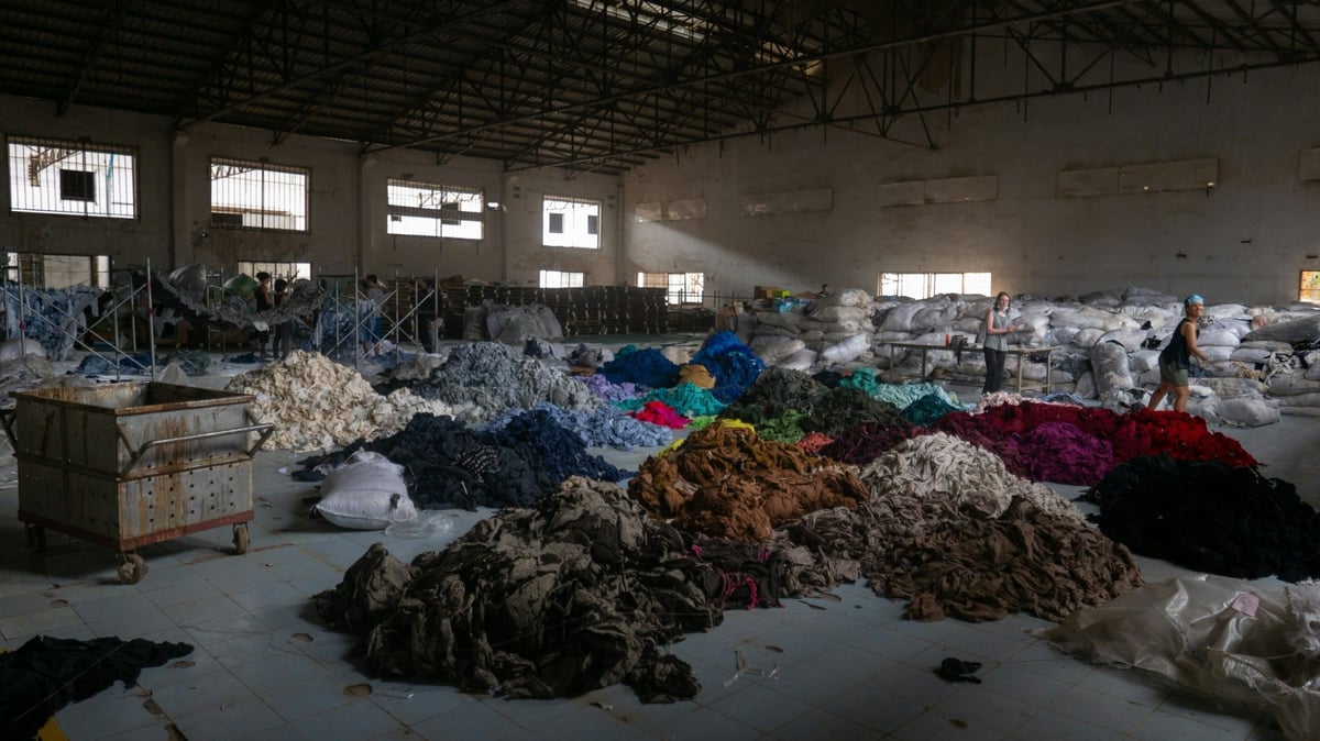 Workers beside piles of coloured textile material inside a processing hall