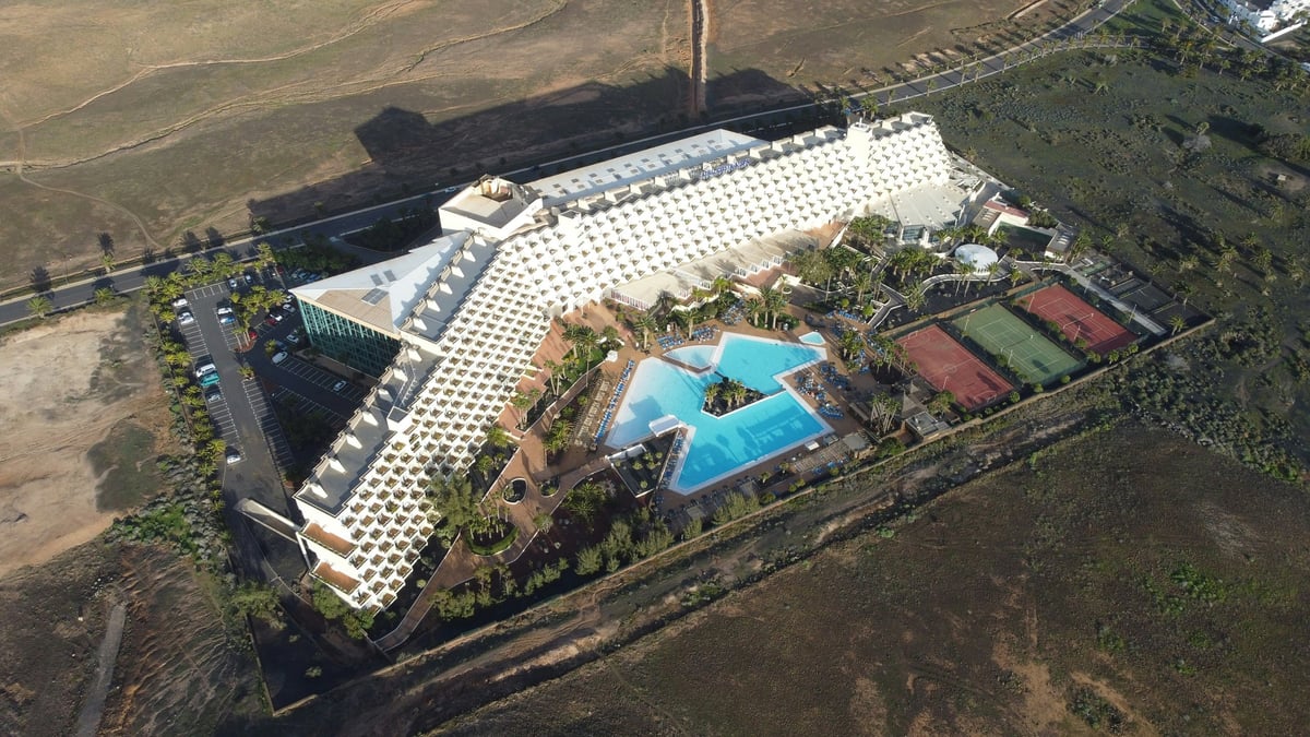 Aerial view of a Lanzarote resort showing hotel rooms, a swimming pool and tennis courts
