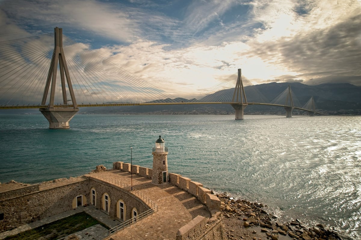 Rion-Antirion Bridge spanning the water in Greece, with a lighthouse in the foreground