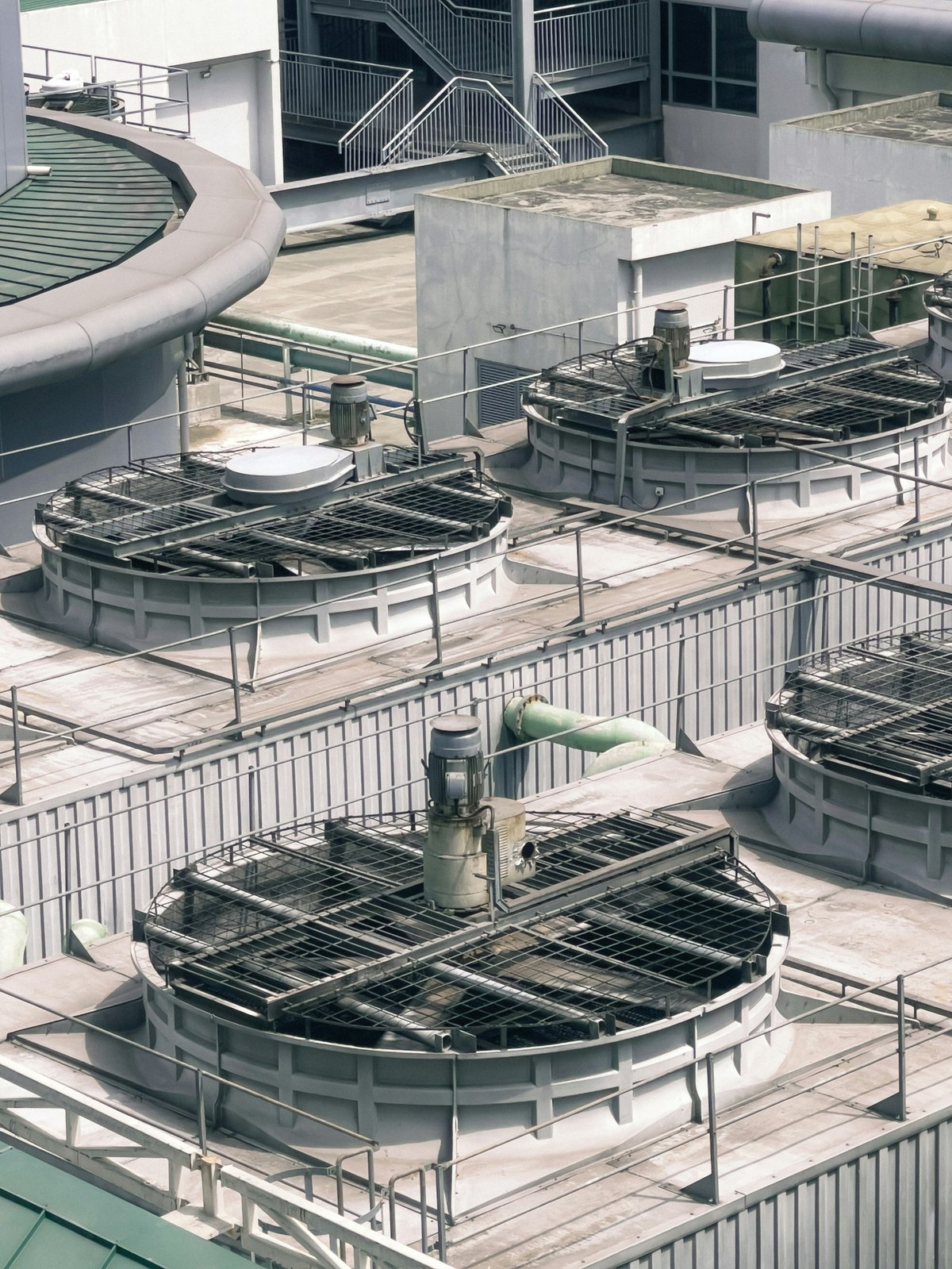 Rooftop cooling towers with large circular fans and connecting pipework